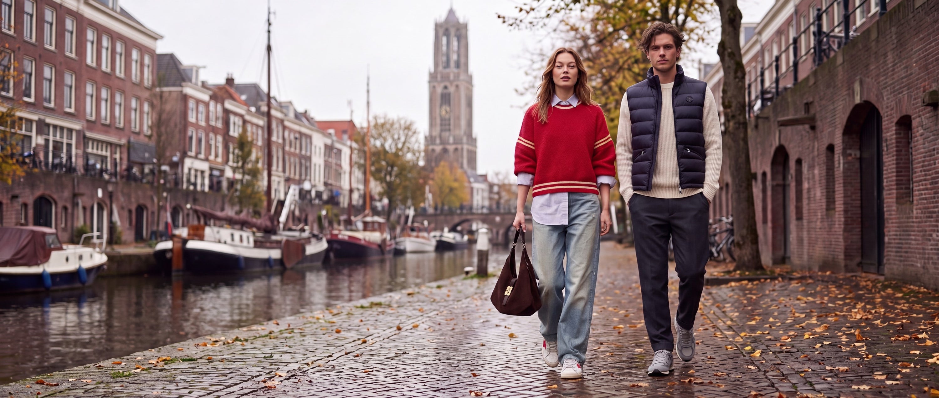 Vrouw en man wandelen langs de Oudegracht in Utrecht met de Domtoren op de achtergrond